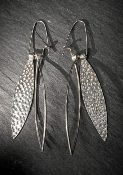 Long dangly silver leaf shape earrings, textured and outline. Dimpled texture handmade from recycled silver in Devon, UK