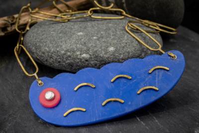 Modern bold contemporary design Blue necklace made from beach plastic with brass chain. Abstract shape with silver and pink accent